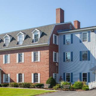 A residential building with brick and siding exterior, featuring multiple windows and dormers.