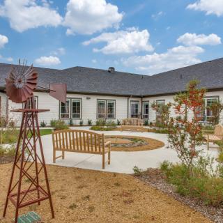 A serene courtyard with benches and a decorative windmill surrounded by landscaped gardens.
