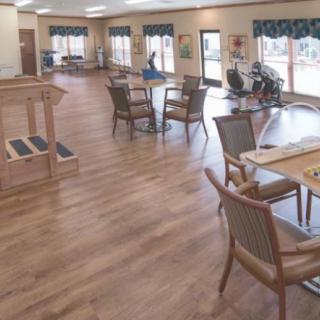 A spacious dining area featuring wooden floors and furniture.