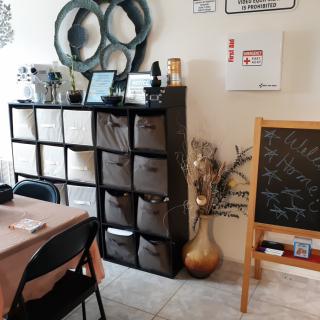 A cozy living space featuring shelving units with storage cubes, decorative art pieces, a chalkboard, and a table.