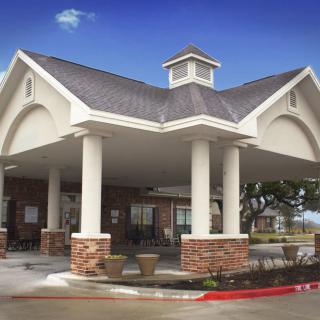 A building entrance featuring large columns and a covered walkway.