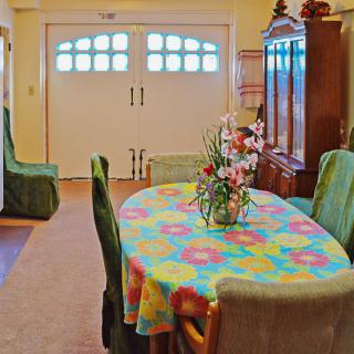 A cozy dining room with a colorful tablecloth and a floral arrangement on the table.