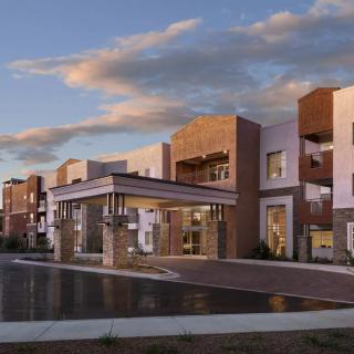 Modern residential building under a partly cloudy sky at sunset.