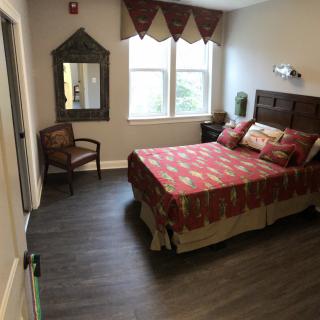 A cozy bedroom with warm decor, featuring a bed, chair, and a large window.