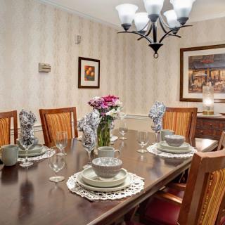 A well-decorated dining room with a set dining table, featuring elegant tableware and a floral centerpiece.