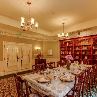 A traditional dining room with an elegantly set table and a large bookshelf.