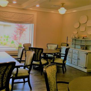 A cozy dining room featuring elegant tables and chairs, with a large window providing natural light.