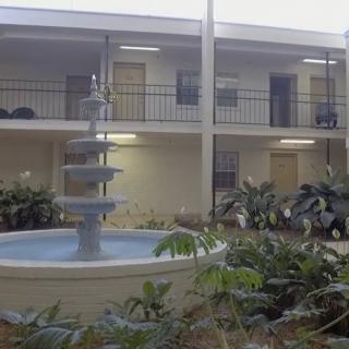 A courtyard with a multi-tiered fountain surrounded by plants and apartment balconies.