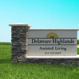 A sign for Delaware Highlands Assisted Living set against a clear blue sky and grass.