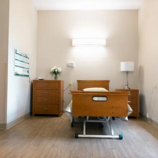 A clean and simple hospital room with a single bed and minimal furnishings.