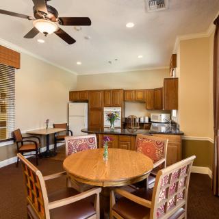 A cozy kitchen and dining area with a round table and chairs, featuring wooden cabinetry, a ceiling fan, and modern appliances.