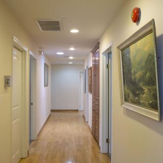 A well-lit hallway in an office with several doors and artwork on the walls.