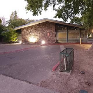 A modern stone-clad building illuminated by soft lights at dusk.