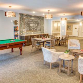 A cozy recreation room featuring a billiards table and comfortable seating areas, with warm lighting enhancing the ambiance.