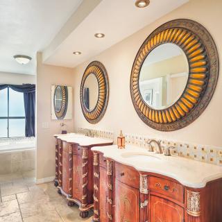 A stylish bathroom featuring a double vanity with wooden cabinets and decorative mirrors.