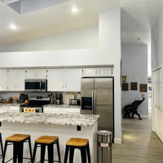 A modern kitchen with a central island and bar stools, featuring stainless steel appliances and sleek design elements.