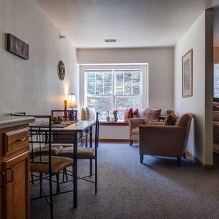 A cozy living room with a dining area, well-lit by natural light from a large window.