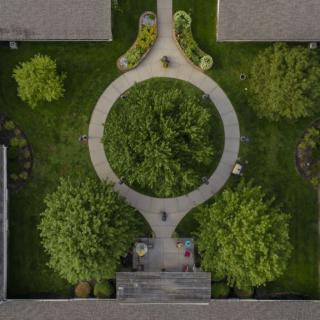 Aerial view of a symmetrical garden featuring circular pathways and lush green trees.
