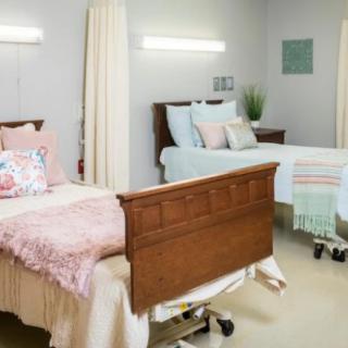 A clean and organized hospital room with two beds separated by a curtain, designed for patient care.