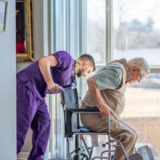 A caregiver assists an elderly person in a wheelchair, providing support and care.