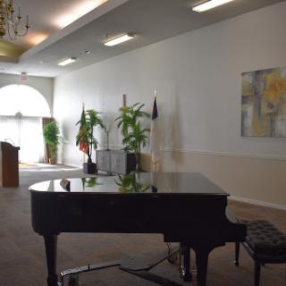 A grand piano positioned in a spacious hall, surrounded by lush plants and elegant decor.