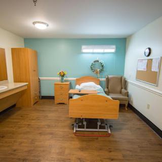 A well-lit hospital room featuring a bed and simple furniture, designed for patient comfort.
