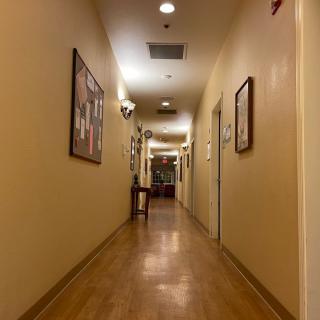 A long, warmly lit hallway with artwork on the walls and a wooden floor.