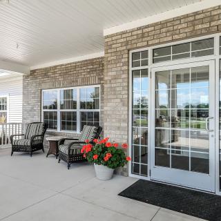 A cozy patio entrance with seating and vibrant flowers.