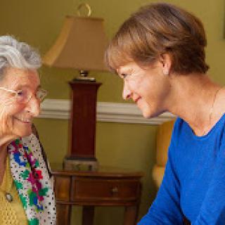 A heartwarming moment between an elderly woman and her caregiver, sharing smiles and connection.