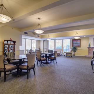 A spacious dining area with tables and chairs, featuring large windows and elegant lighting.