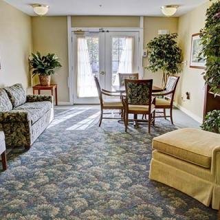 A cozy living room with a sofa, table, chairs, and potted plants.