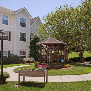 A peaceful garden with a gazebo beside a residential building.