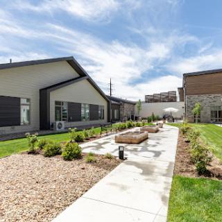 A serene outdoor space featuring modern buildings, a landscaped garden, and a clear blue sky.