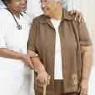 A caregiver assists an elderly person walking with a cane.