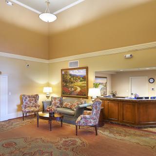 A spacious lobby with a reception desk, seating area, and decorative painting.
