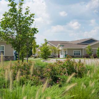 A picturesque residential area with modern houses, surrounded by lush greenery and a clear sky.
