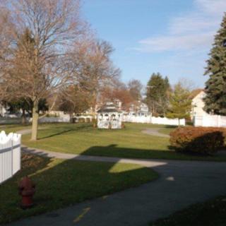 A peaceful suburban park with a gazebo and surrounding trees on a sunny day.