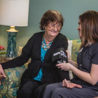 A healthcare professional conducts an interview with an elderly woman, both smiling and engaged in conversation.