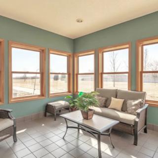 A bright and cozy sunroom with comfortable seating, surrounded by large windows allowing plenty of natural light.