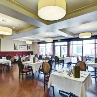 A spacious and elegantly decorated restaurant dining area with neatly set tables and ambient lighting.