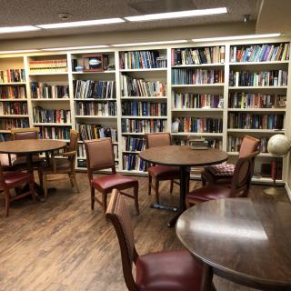 A cozy library study area with bookshelves, round tables, and chairs.
