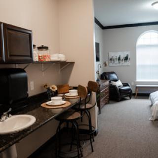 A cozy studio apartment featuring a compact kitchen area with bar stools and a living space blending into a bedroom setup.