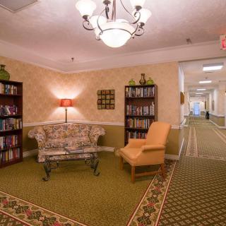 A cozy lobby area with bookshelves, a sofa, and an armchair under a chandelier.