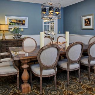 Elegant dining room with a wooden table and upholstered chairs, featuring classic decor and warm lighting.