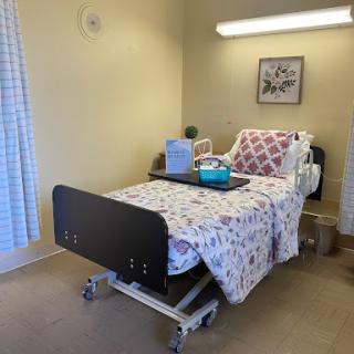 A clean and simple hospital room featuring an adjustable bed, medical supplies, and soft lighting.