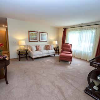 A cozy living room featuring a comfortable sofa and two armchairs, illuminated by natural light from large windows.