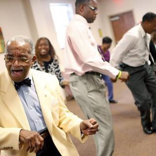A group of people dancing indoors, dressed in formal attire and enjoying a celebration.