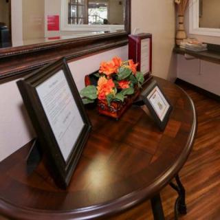 A reception area with framed documents and flowers on a wooden table.