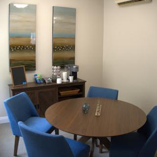 A modern meeting room featuring a round table surrounded by blue chairs and decorative artwork on the walls.