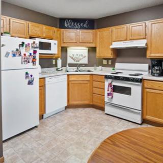 A cozy kitchen with wooden cabinets, featuring modern appliances like a refrigerator, stove, microwave, and dishwasher.